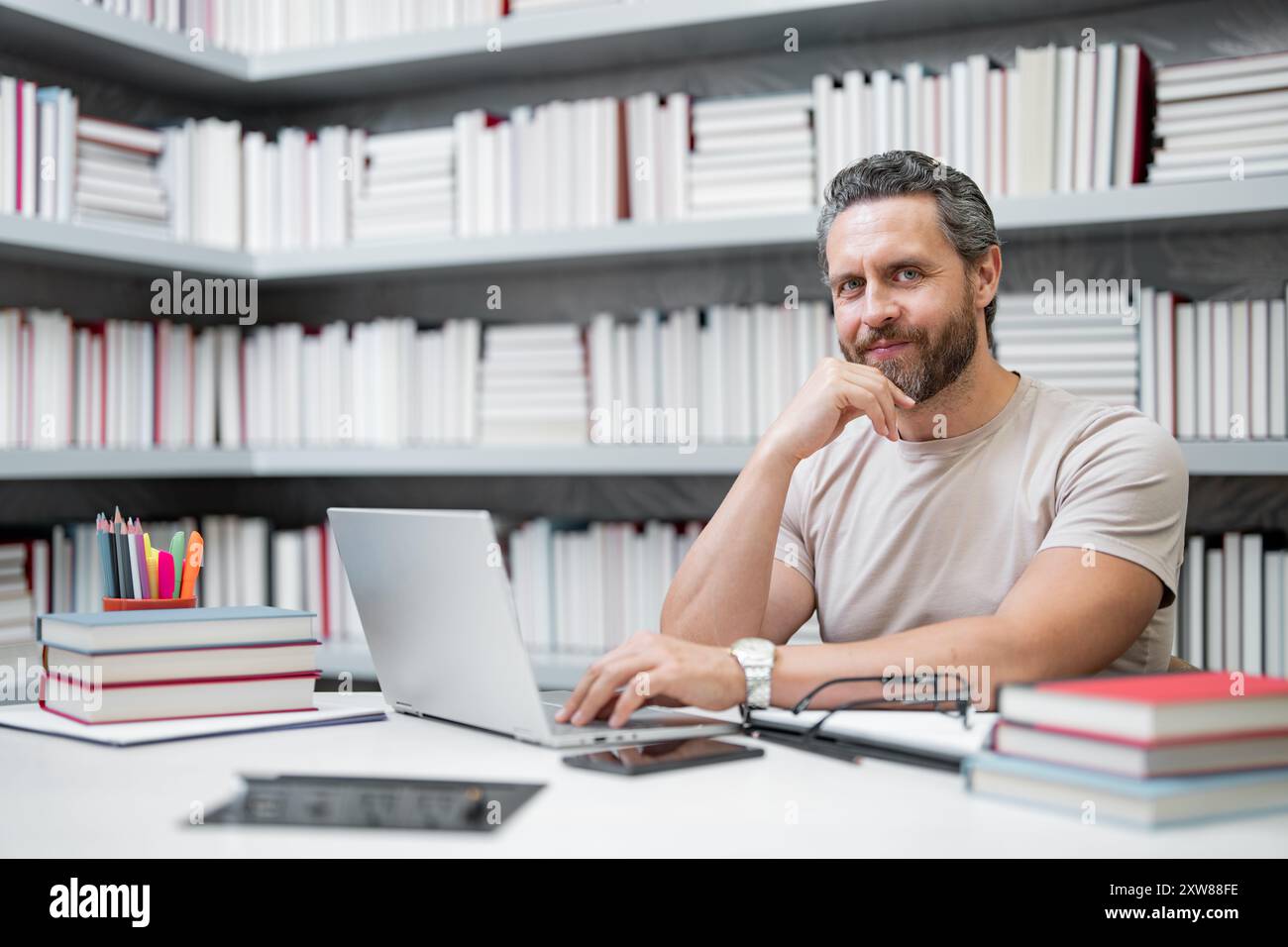 Enseignant travail sur ordinateur portable en classe. Connaissance et éducation avec beau professeur. Professeur avec livre en classe. Homme en leçon en classe. Enseignants Banque D'Images