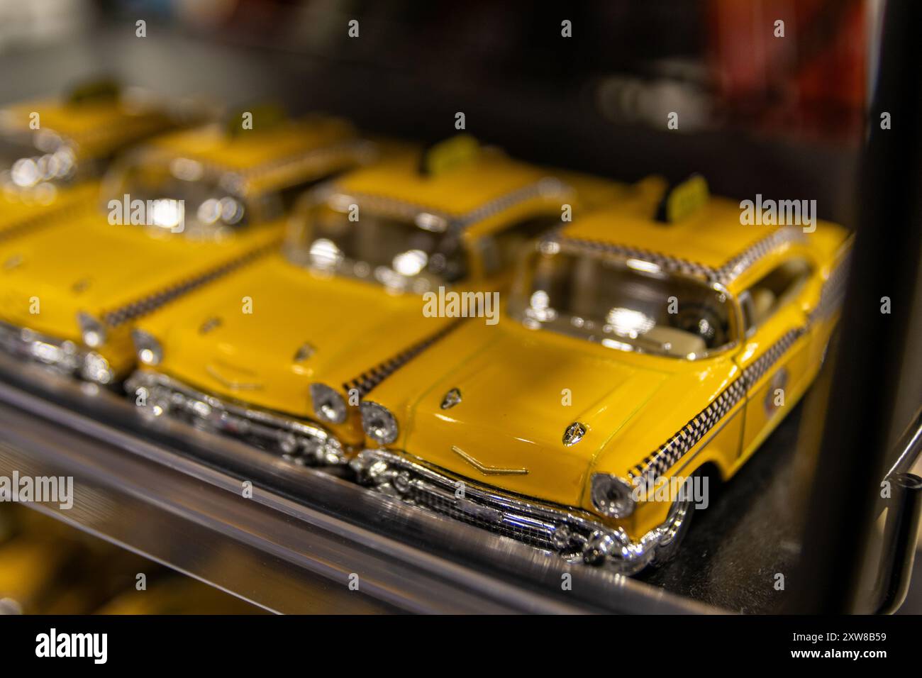 Les modèles de voitures jaune vif avec des détails chromés sont soigneusement alignés sur une étagère, design automobile classique. Prise à Toronto, Canada. Banque D'Images