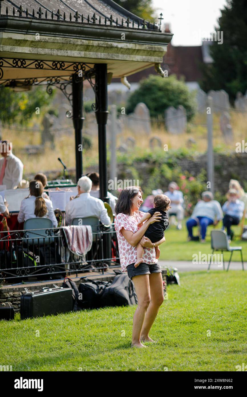 Les Burys, Godalming. 18 août 2024. Un après-midi chaud et ensoleillé pour les Home Counties. Les gens apprécient la musique dans le parc au Godalming Bandstand dans le Surrey. Tous les dimanches après-midi pendant les mois d'été, de la musique live est jouée avec une variété de genres couverts. Cet après-midi, c'était le tour de 'The Band of the Surrey Yeomanry', parrainé par BL Vision de Farncombe. Crédit : james jagger/Alamy Live News Banque D'Images