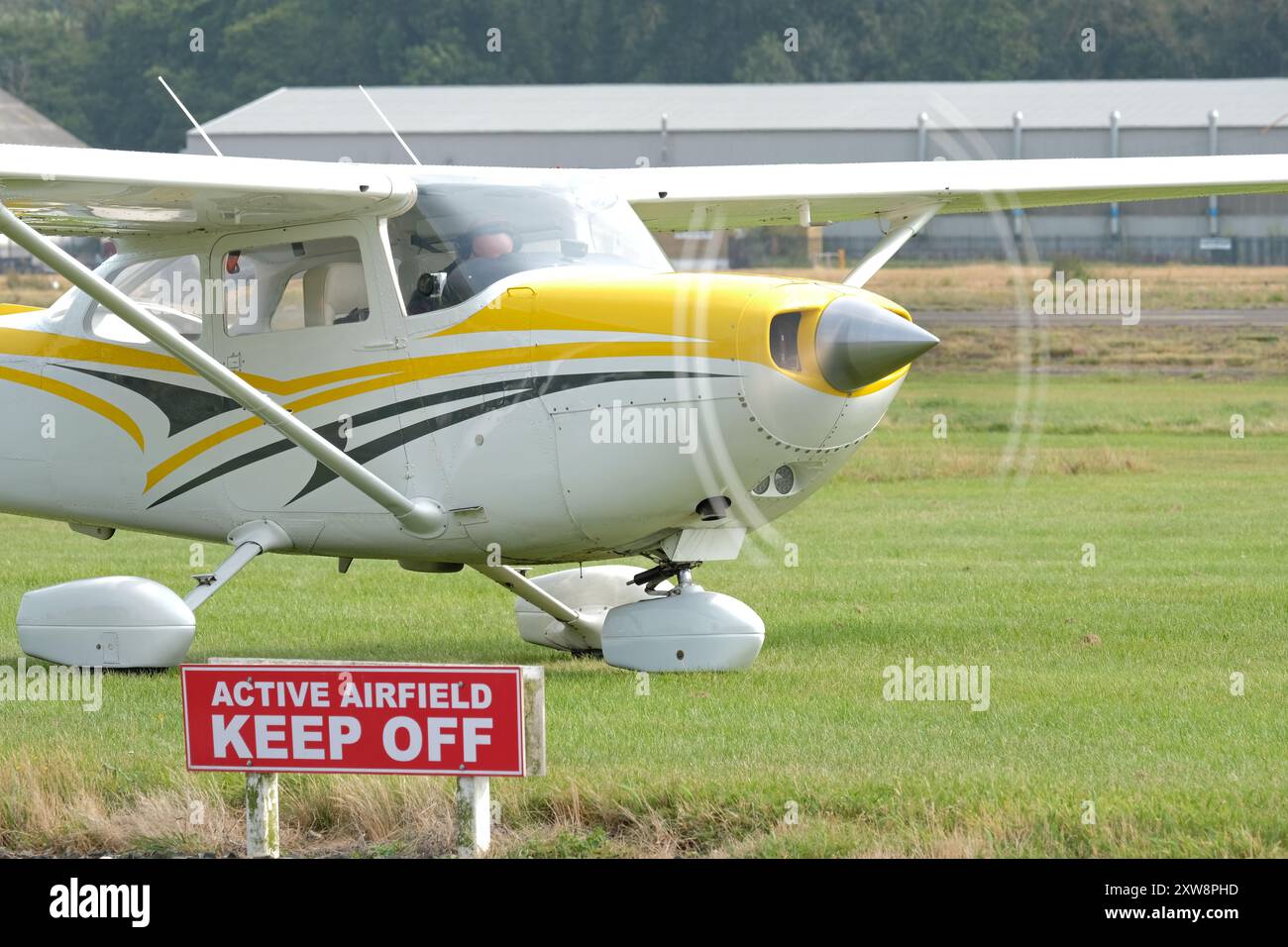Avion léger Cessna 172 avec hélice tournant à côté d'un panneau d'avertissement de sécurité de vol de l'aérodrome actif Keep Off Banque D'Images Avion léger Cessna 172 avec hélice tournant à côté d'un panneau d'avertissement de sécurité de vol de l'aérodrome actif Keep Off Banque D'Images