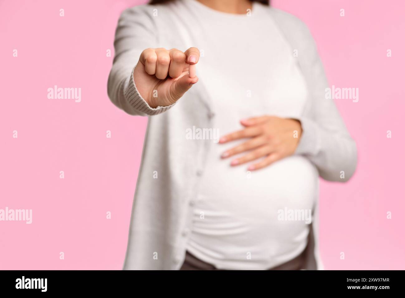 Fille enceinte méconnaissable montrant la pilule à Camera Standing, fond blanc Banque D'Images