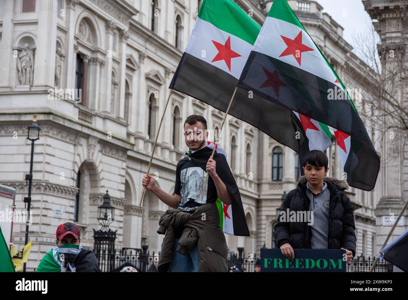 Londres, Royaume-Uni. 16 mars 2024. Un manifestant se tient debout avec des drapeaux devant Downing Street pendant la manifestation. Un petit groupe de la diaspora syrienne s’est réuni devant Downing Street, à Londres, pour le 13e anniversaire de la révolution syrienne. Elle est également connue sous le nom de révolution syrienne de la dignité. Le soulèvement était contre le président Bachar al-Assad et sa dictature. (Crédit image : © Krisztian Elek/SOPA images via ZUMA Press Wire) USAGE ÉDITORIAL SEULEMENT! Non destiné à UN USAGE commercial ! Banque D'Images