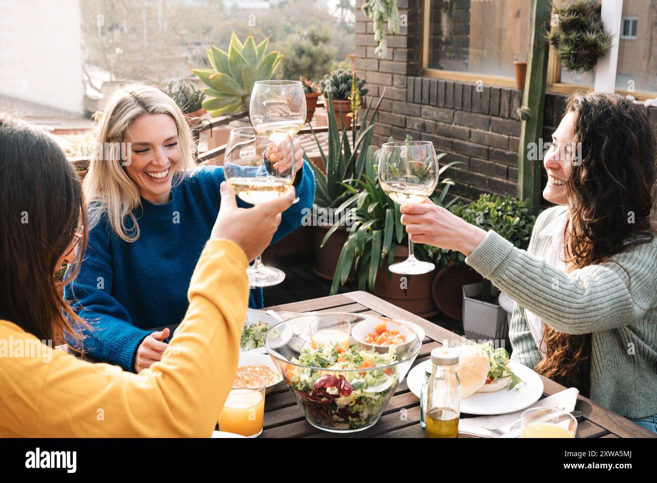 Dîner entre amis, groupe de femmes célébrant à l'extérieur restaurant végétalien. Les jeunes mangeant dans le patio de la maison Banque D'Images