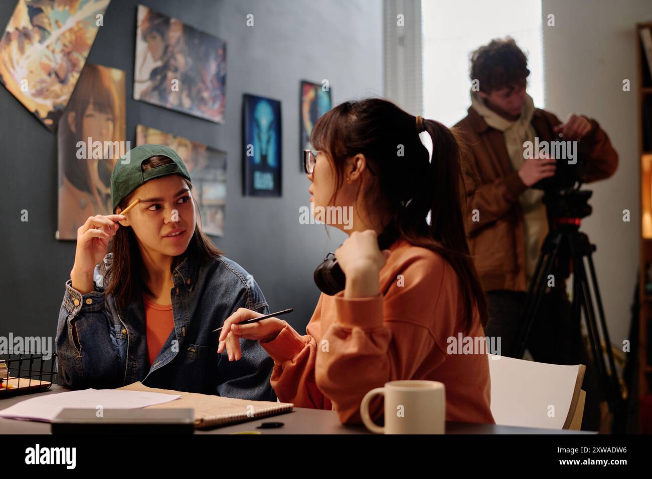 Portrait de deux femmes asiatiques engagées dans une conversation réfléchie sur un projet artistique dans un studio urbain Banque D'Images