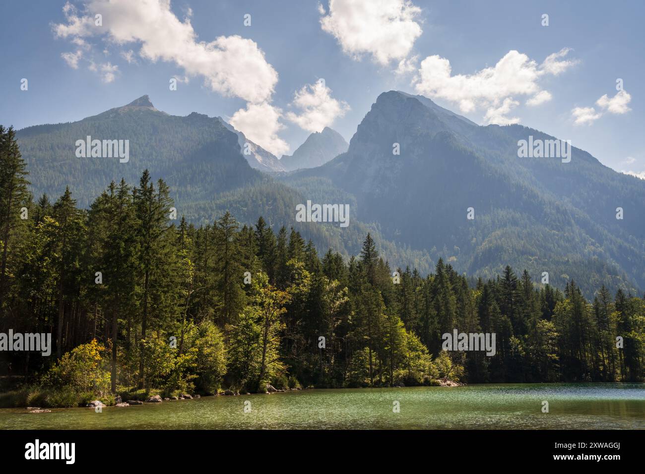 Un lac alpin calme, entouré de forêts, s'étend vers une vallée montagneuse brumeuse, avec une petite barque, près de Ramsau bei Berchtesgaden, en Bavière, Allemagne. Banque D'Images