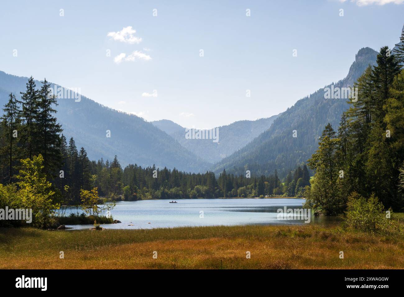 Un lac alpin calme, entouré de forêts, s'étend vers une vallée montagneuse brumeuse, avec une petite barque, près de Ramsau bei Berchtesgaden, en Bavière, Allemagne. Banque D'Images