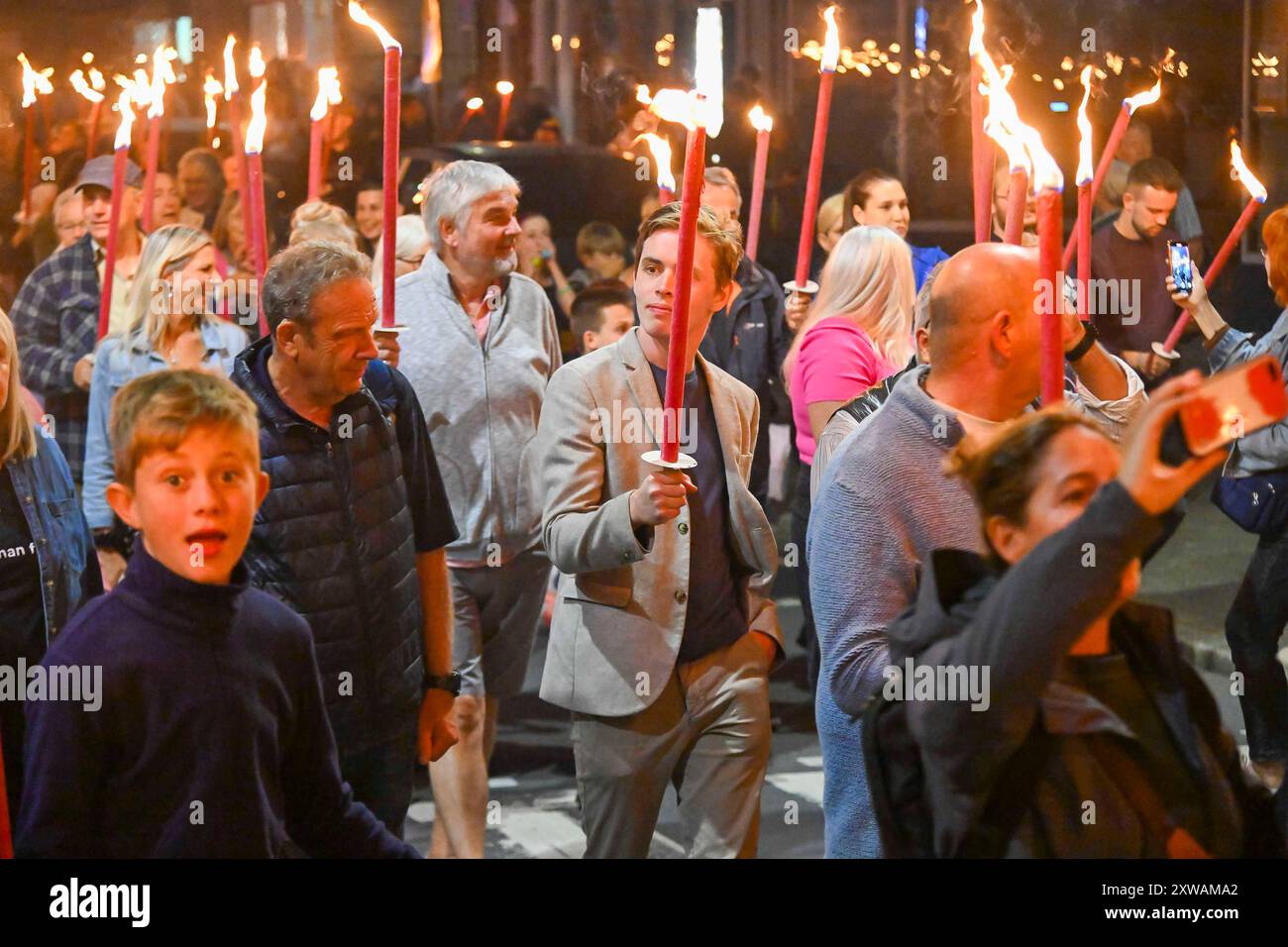 Bridport, Dorset, Royaume-Uni. 18 août 2024. Des centaines de personnes portant des torches flamboyantes participent à la procession annuelle des torches du carnaval de Bridport. La procession de Two Mile a commencé à l'hôtel de ville de Bridport et s'est terminée à East Beach à West Bay dans le Dorset. Crédit photo : Graham Hunt/Alamy Live News Banque D'Images