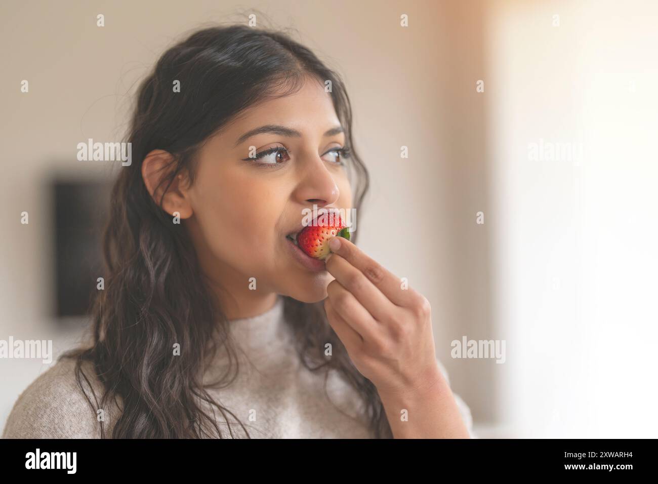 femme indienne mangeant des fraises à la maison Banque D'Images