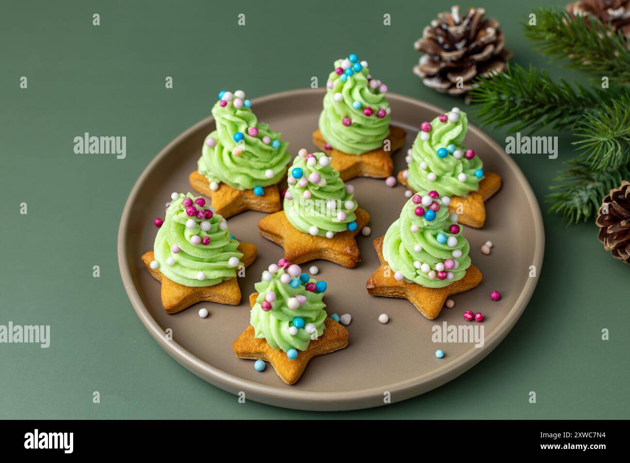 Biscuits sapin de Noël avec glaçage vert et saupoudres sur assiette. Banque D'Images