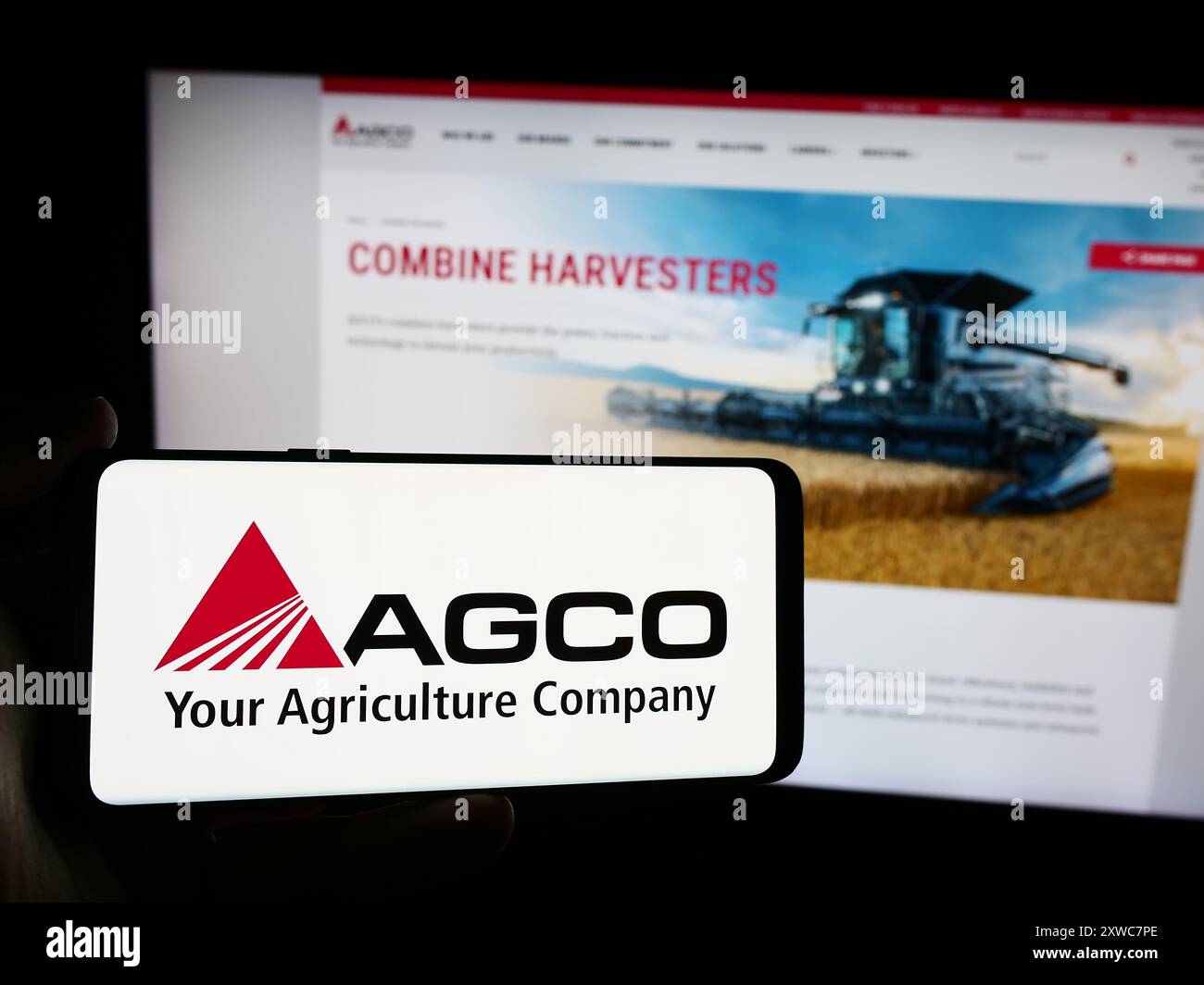 Personne tenant le téléphone portable avec le logo de la société américaine de machines agricoles AGCO Corporation devant la page Web. Concentrez-vous sur l'affichage du téléphone. Banque D'Images