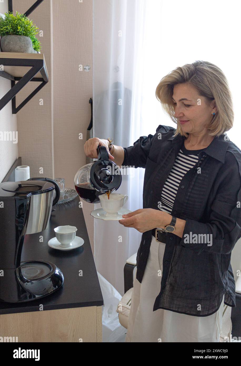 femme d'affaires, blonde 45-50 ans, verse le café dans des tasses, Banque D'Images femme d'affaires, blonde 45-50 ans, verse le café dans des tasses, Banque D'Images