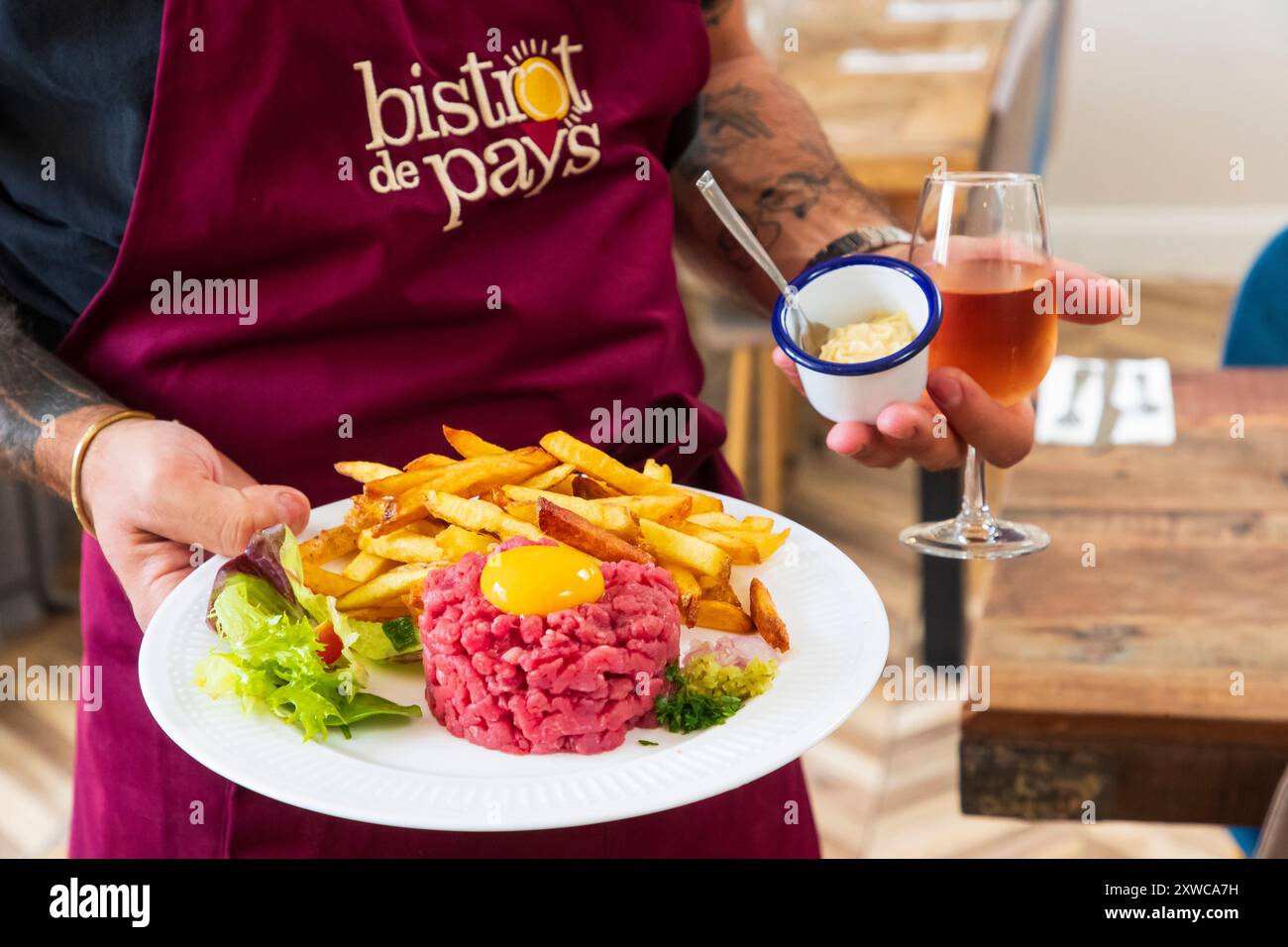 La Buvette, bar à Saint-Maximin (nord de la France). Serveur apportant un steak tartare avec des frites Banque D'Images