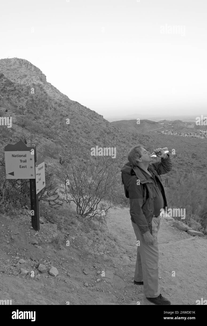 Homme caucasien, 50-60 ans, boire de l'eau avant de faire une randonnée le long du Telegraph Pass Trail au South Mountain Park à Phoenix, Arizona, États-Unis. Banque D'Images