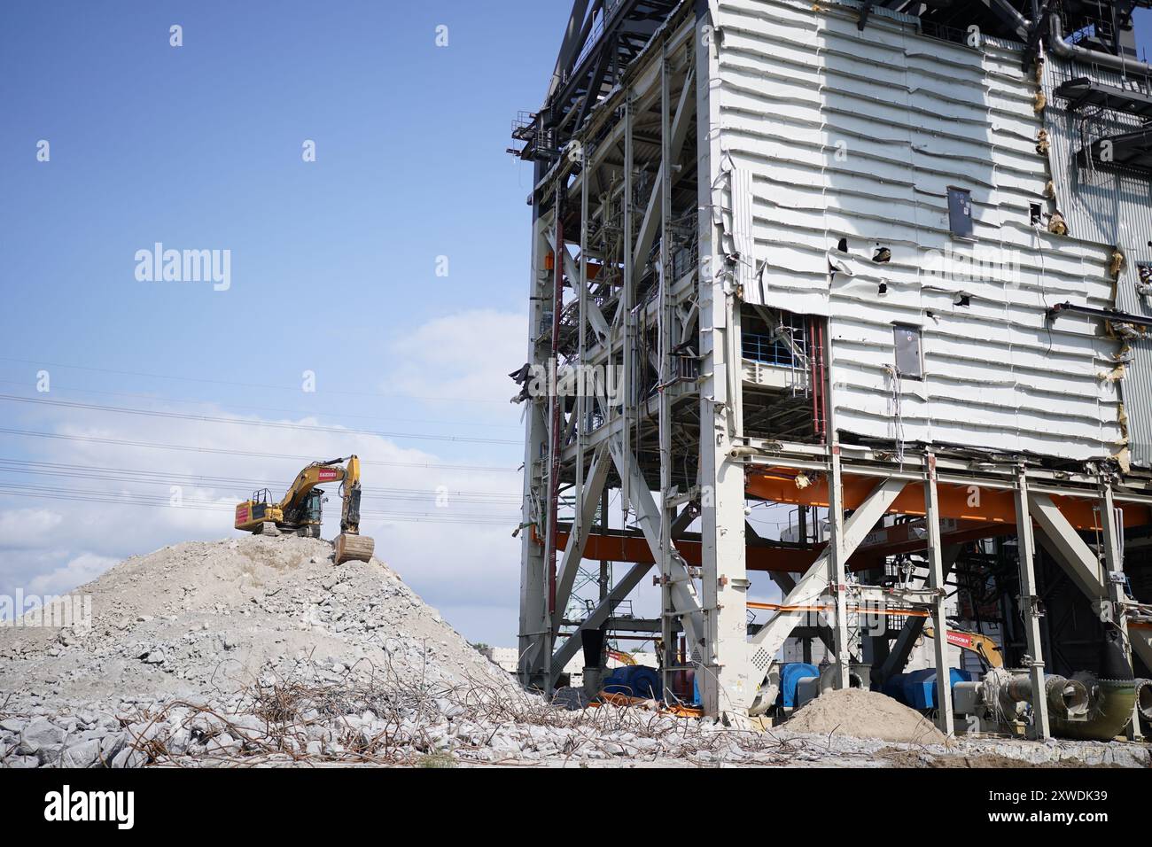 Hambourg, Allemagne. 19 août 2024. Une excavatrice se trouve à côté d'un bâtiment en ruine sur le site de l'ancienne centrale au charbon et actuel Moorburg Energy Hub. Au cours de cette visite, le ministre de l'économie Habeck a pris connaissance des projets d'hydrogène de Hambourg sur le site de l'ancienne centrale au charbon. Crédit : Marcus Brandt/dpa/Alamy Live News Banque D'Images