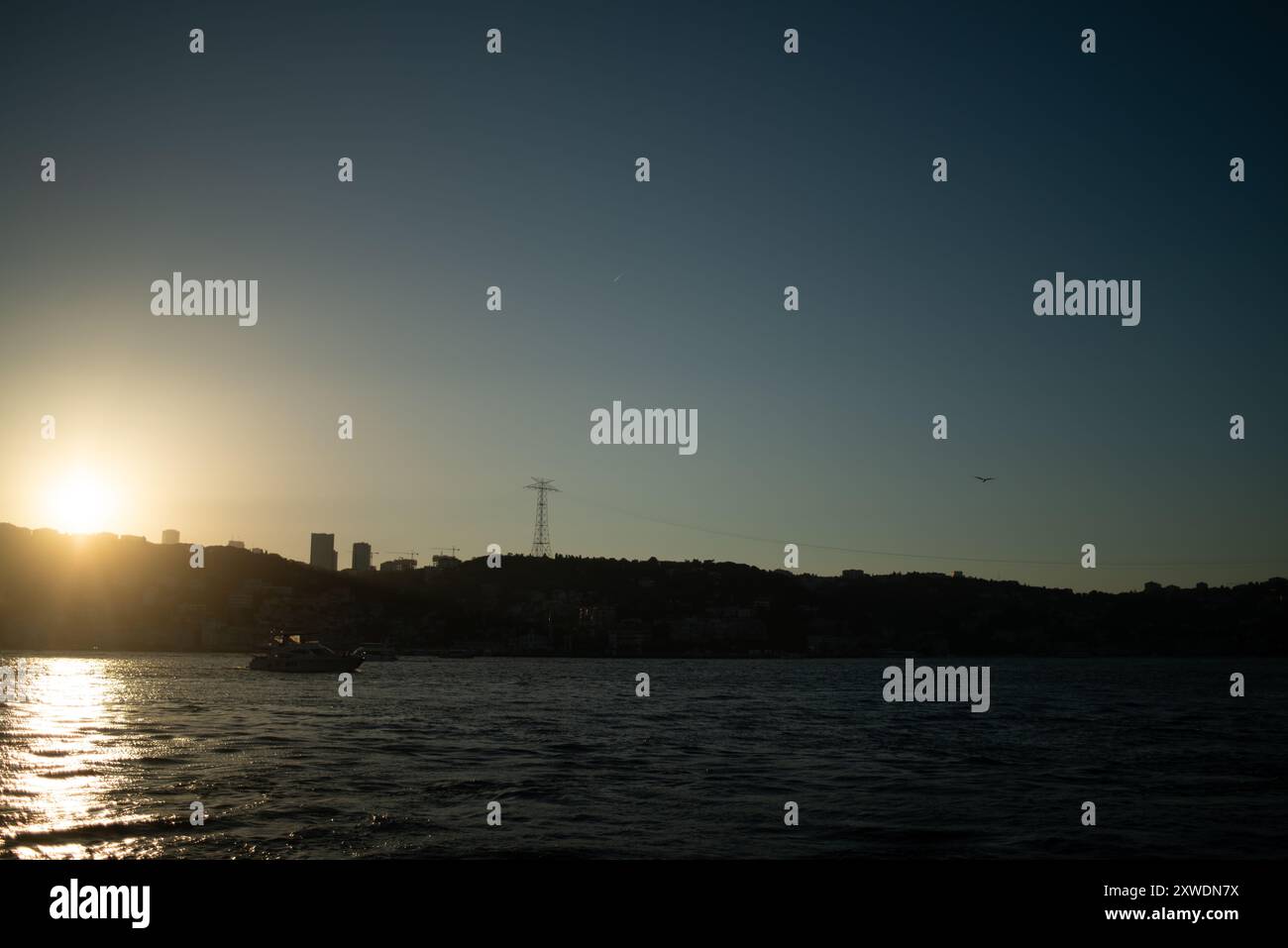 Une vue imprenable sur le Bosphore d'Istanbul au coucher du soleil, avec l'emblématique drapeau turc agitant fièrement. La lumière dorée se reflète sur l'eau, hig Banque D'Images Une vue imprenable sur le Bosphore d'Istanbul au coucher du soleil, avec l'emblématique drapeau turc agitant fièrement. La lumière dorée se reflète sur l'eau, hig Banque D'Images