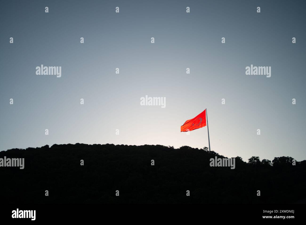 Une image puissante du drapeau turc agitant fièrement au sommet d'une montagne, symbolisant la force, la liberté et la fierté nationale, sur fond de vaste Banque D'Images Une image puissante du drapeau turc agitant fièrement au sommet d'une montagne, symbolisant la force, la liberté et la fierté nationale, sur fond de vaste Banque D'Images