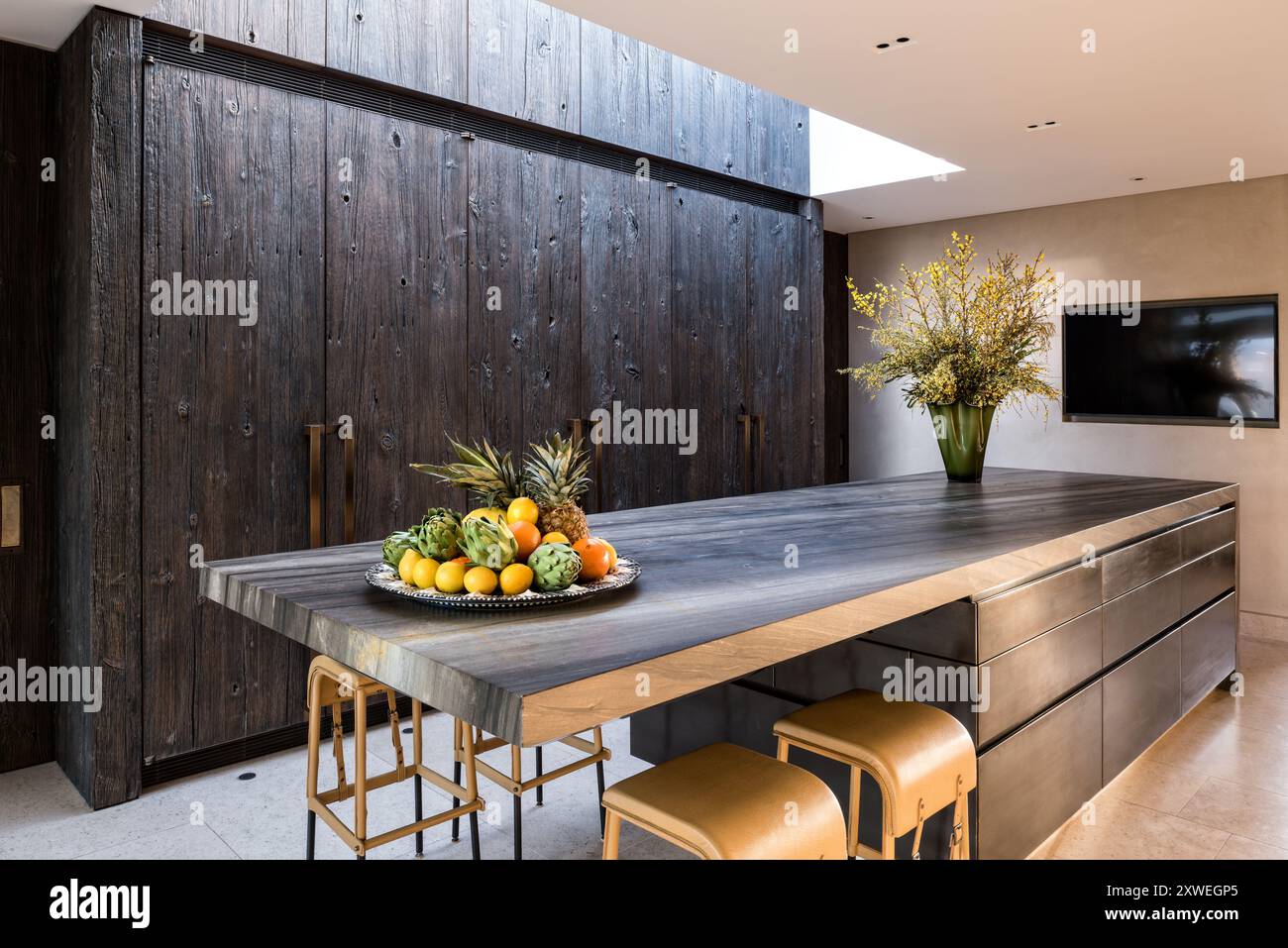 Balai jaune (Cytisus scoparius) et fruits sur le plan de travail de la cuisine avec des cupbaords taillés rugueux dans la maison britannique moderne de luxe. Londres, Royaume-Uni Banque D'Images