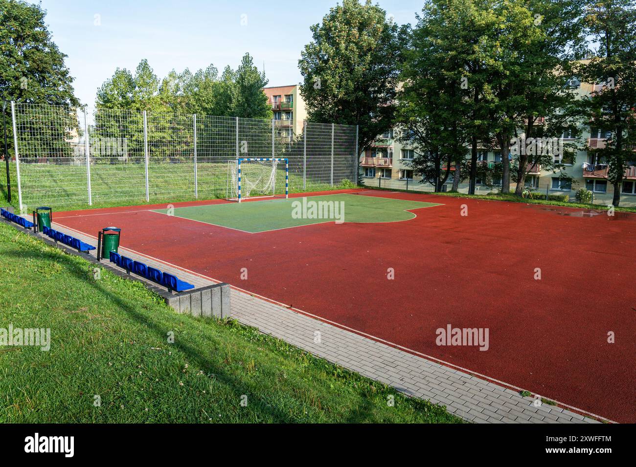 Terrain de sport urbain bien entretenu avec un objectif et une surface rouge vibrante dans un quartier résidentiel par une journée ensoleillée Banque D'Images
