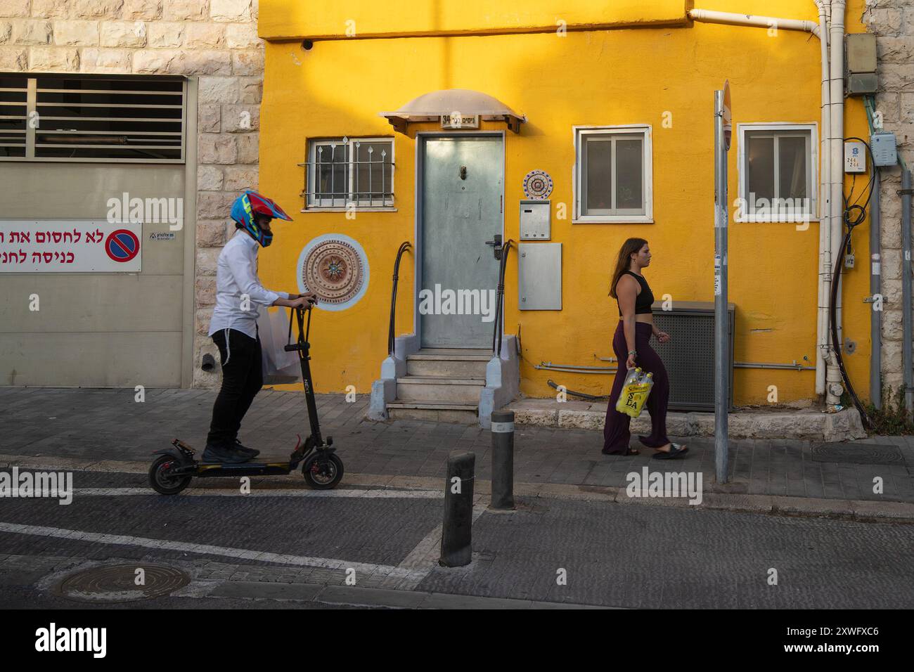 Jérusalem, Israël - 20 juin 2023 : un jeune homme juif orthodoxe sur un scooter électrique, et une jeune femme habillée de manière révélatrice, sur un Jérusalem, I. Banque D'Images