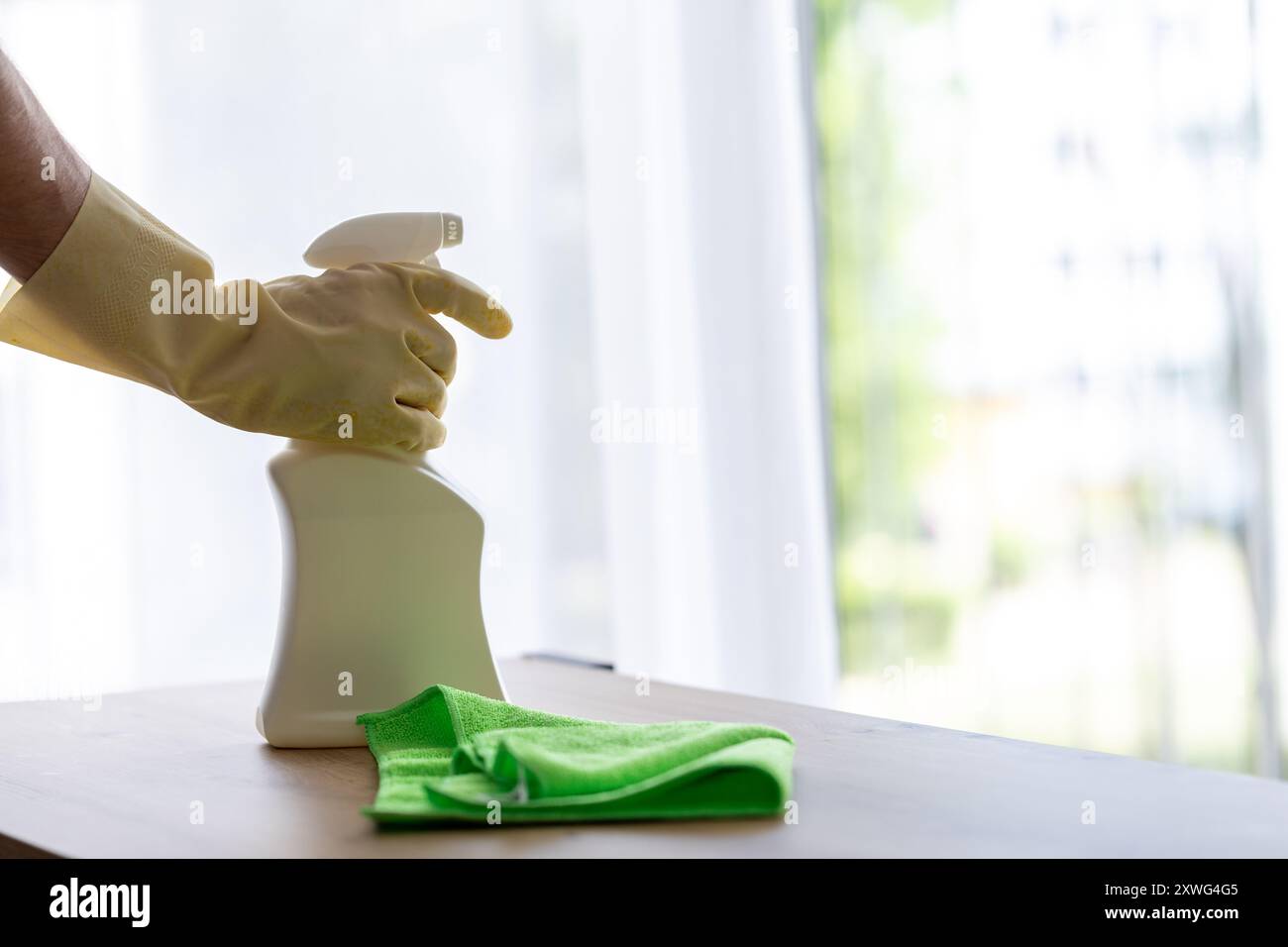 homme en gants de protection jaunes saupoudrant avec un agent nettoyant. nettoyage dans l'appartement ou la chambre d'hôtel Banque D'Images