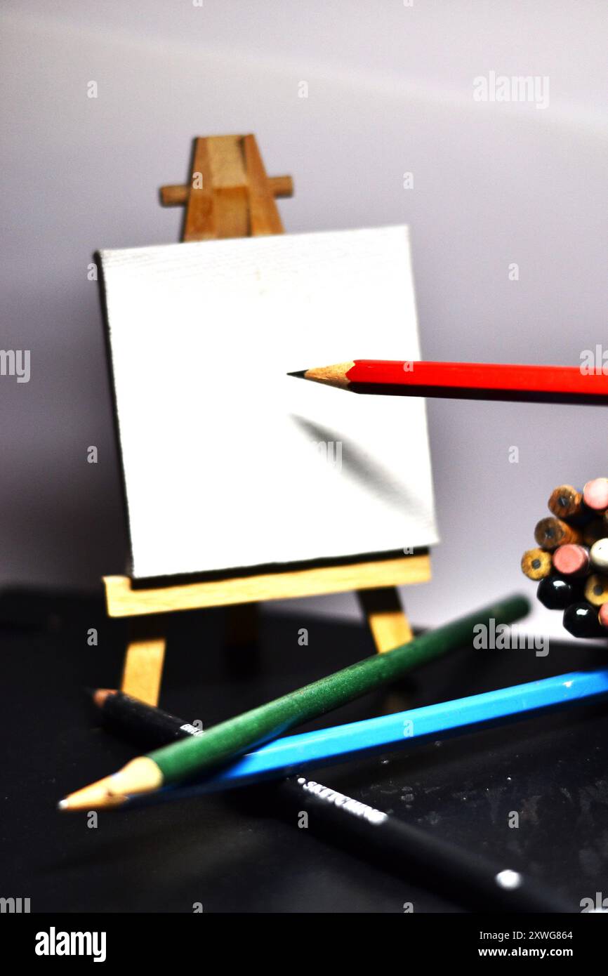 Crayon rouge posé sur toile blanche tenue dans un chevalet, prêt à dessiner Banque D'Images