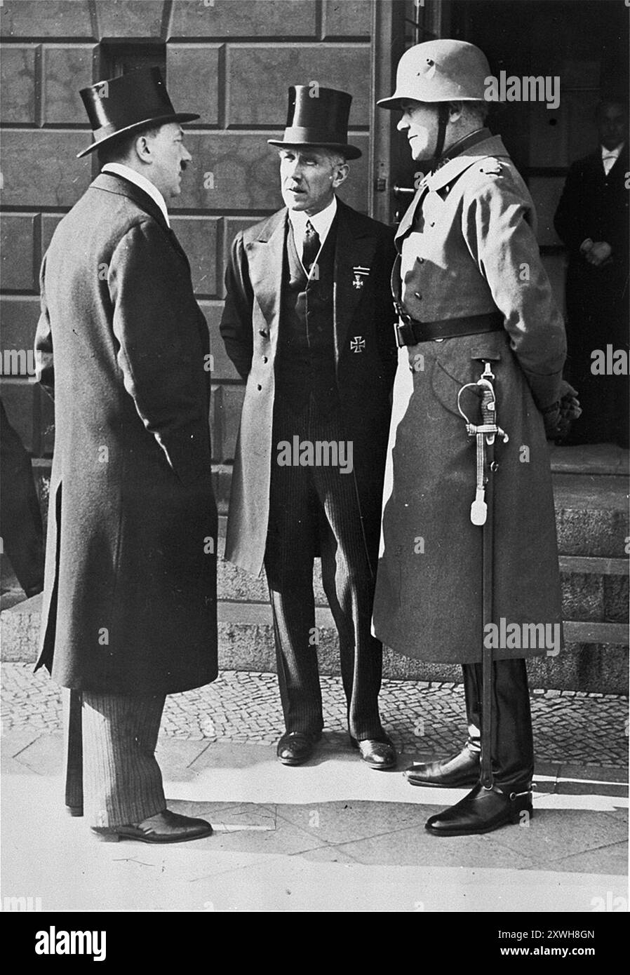 Le chancelier Adolf Hitler, le vice-chancelier von Papen et le ministre de la Défense von Blomberg attendent devant l'opéra le président du Reichs le jour de deuil national allemand. Cet événement a eu lieu juste après la nomination d'Hitler comme chancelier. Dans l'un des masterstrokes d'Hitler, il se tenait devant von Hindenberg alors qu'il quittait l'événement et, la tête inclinée, serrait révéremment sa main. La photo qui en résulte a beaucoup contribué à créer l'illusion que Hindenburg approuvait Hitler, ce qui n'était pas vrai, et que Hitler respectait le président vieillissant, ce qui n'était pas non plus vrai. La photo est datée du 1933 mars 12. Banque D'Images