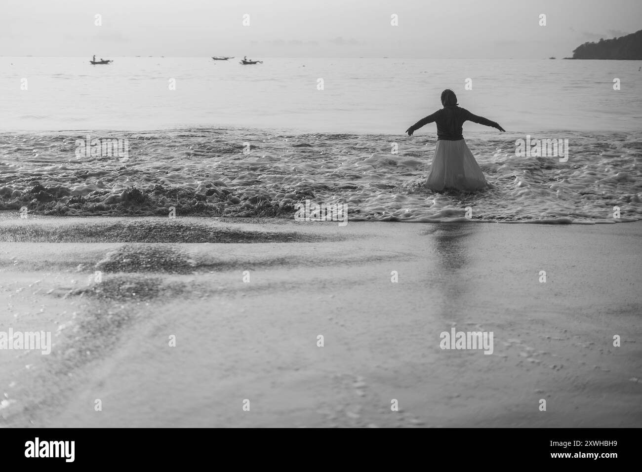 Dansant joyeusement dans les vagues ensoleillées de la plage, elle embrasse le pur bonheur et la liberté, ses mouvements insouciants reflétant l'esprit vibrant et radieux du bord de mer. Banque D'Images