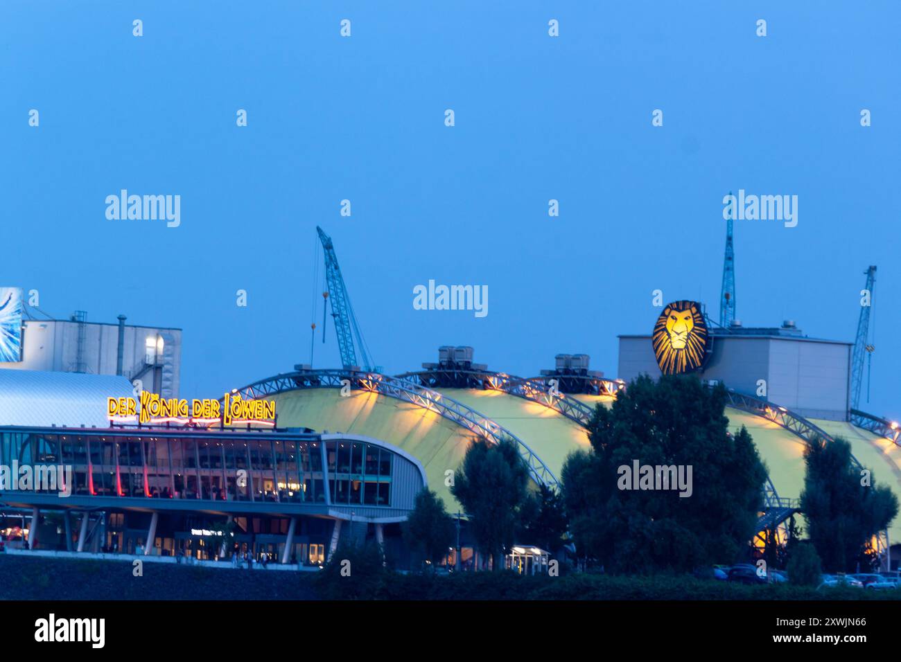 HAMBOURG, ALLEMAGNE - 15 AOÛT 2024 : soirée dans le port de Hambourg. Au premier plan sont illuminés des navires, en arrière-plan est le théâtre où le mus Banque D'Images