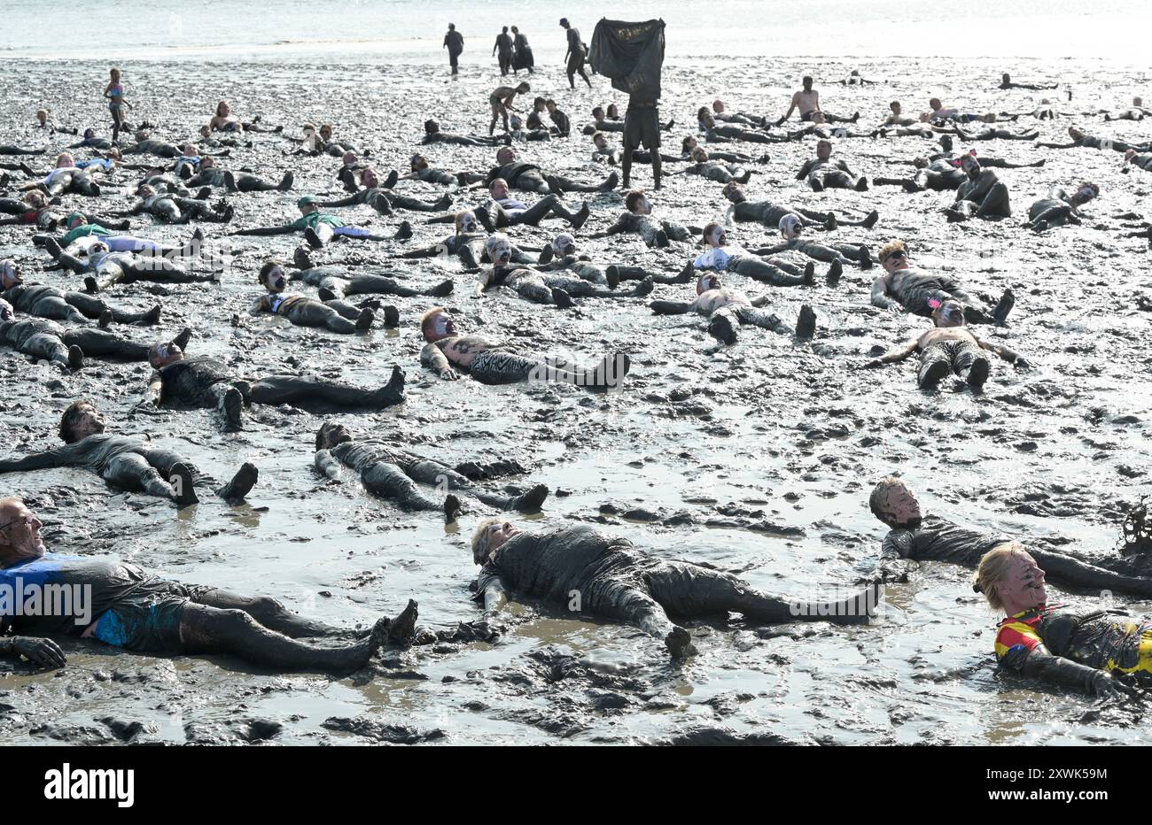 ALLEMAGNE, Schleswig-Holstein, Brunsbuettel, été 2024, festival des Wattolümpiade jeux olympiques de wadden en mer de wadden en mer du Nord allemande, beaucoup de gens ont un bain de wadden dans la boue à marée basse / DEUTSCHLAND, Brunsbüttel, Watt Olümpiade im Wattenmeer, Teilnehmer beim gemeinsamen Schlammbad im Schlick BEI Ebbe Banque D'Images