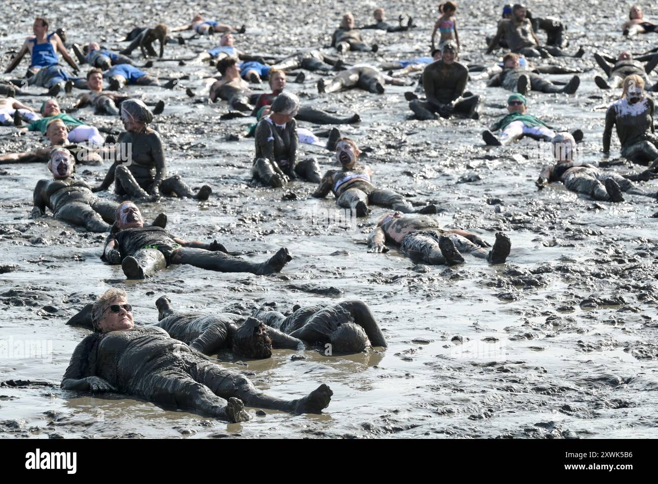 ALLEMAGNE, Schleswig-Holstein, Brunsbuettel, été 2024, festival des Wattolümpiade jeux olympiques de wadden en mer de wadden en mer du Nord allemande, beaucoup de gens ont un bain de wadden dans la boue à marée basse / DEUTSCHLAND, Brunsbüttel, Watt Olümpiade im Wattenmeer, Teilnehmer beim gemeinsamen Schlammbad im Schlick BEI Ebbe Banque D'Images