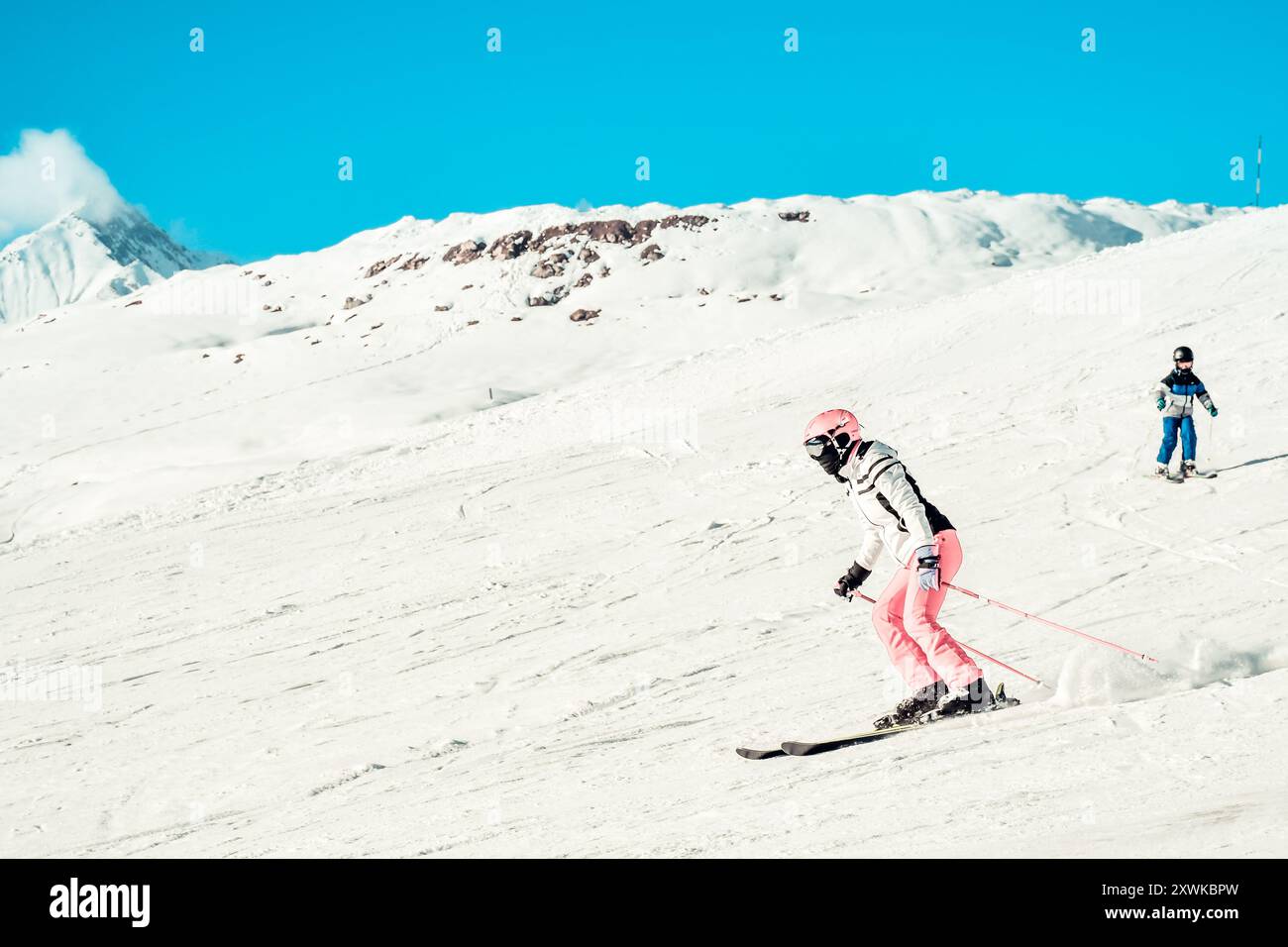 Femme mère skieur avec enfant fils garçon sur la piste ski descente rapide mouvement dans les Alpes. Vacances d'hiver actives, ski en descente dans le ciel bleu ensoleillé jour. SK Banque D'Images