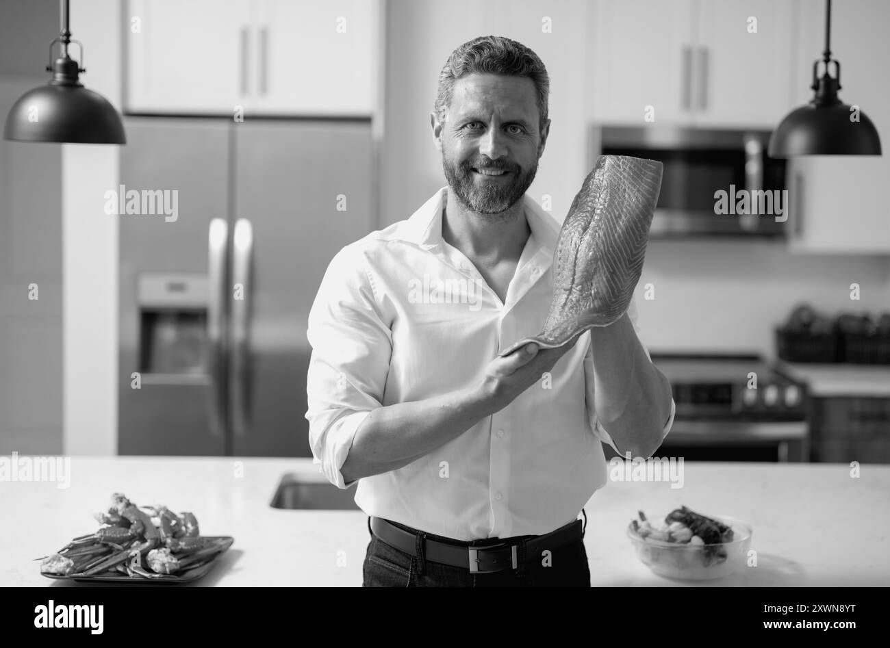 Homme avec filet de saumon cru à la cuisine. Chef cuisant un filet de poisson. Le gros saumon est entre les mains du chef cuisinier. Chef cuisinier qui cuisine le crabe des fruits de mer et Banque D'Images