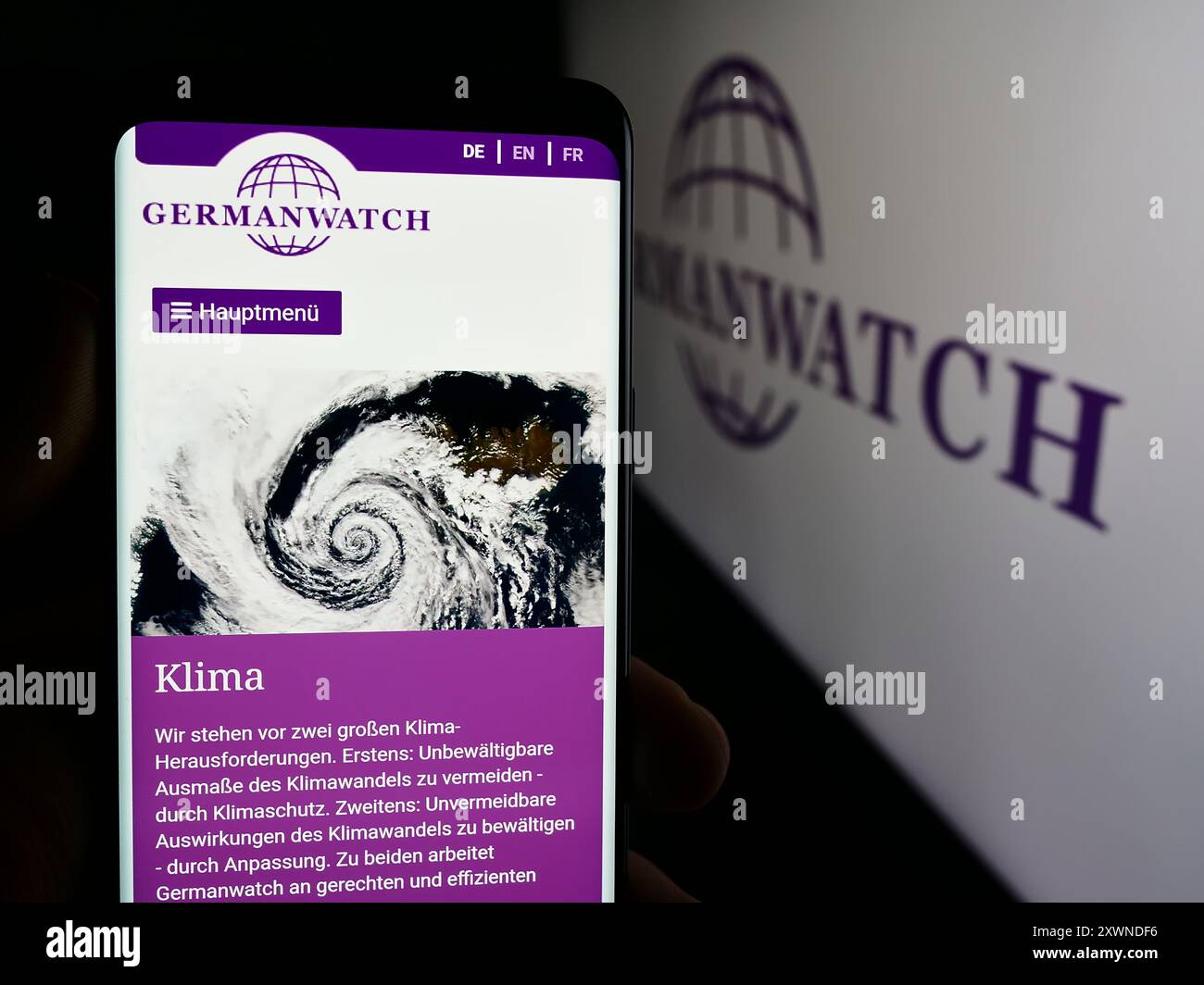 Personne tenant un téléphone portable avec la page web de l'organisation non gouvernementale allemande Germanwatch e.V. devant le logo. Concentrez-vous sur le centre de l'écran du téléphone. Banque D'Images