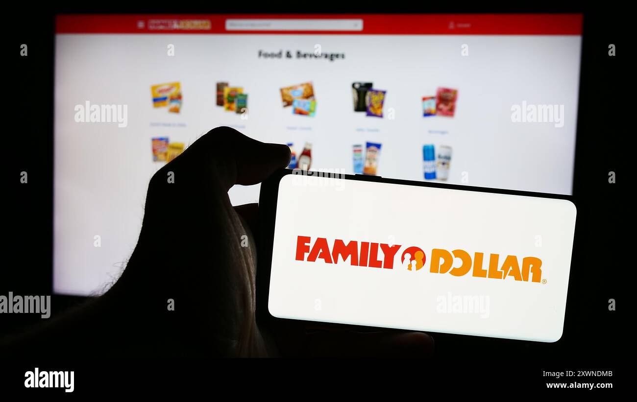 Personne tenant le téléphone portable avec le logo de la société américaine de magasin de variété Family Dollar Stores Inc en face de la page Web. Concentrez-vous sur l'affichage du téléphone. Banque D'Images