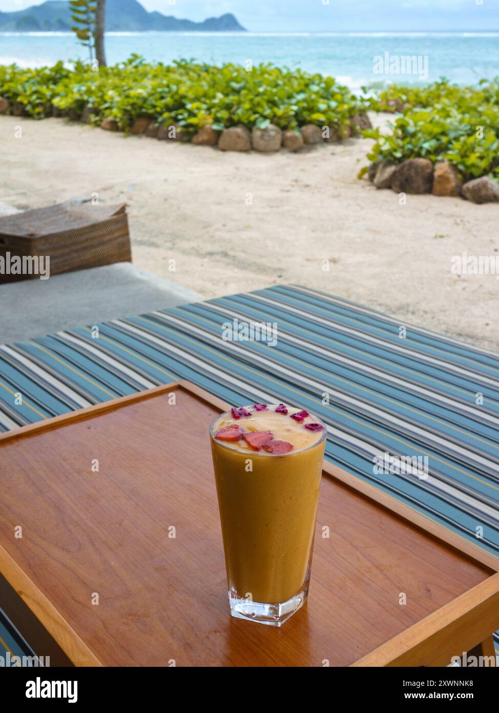 Boisson de jus de fruits tropicaux avec fruits épelant le mot bonjour sur une table près d'une plage tropicale, Indonésie Banque D'Images