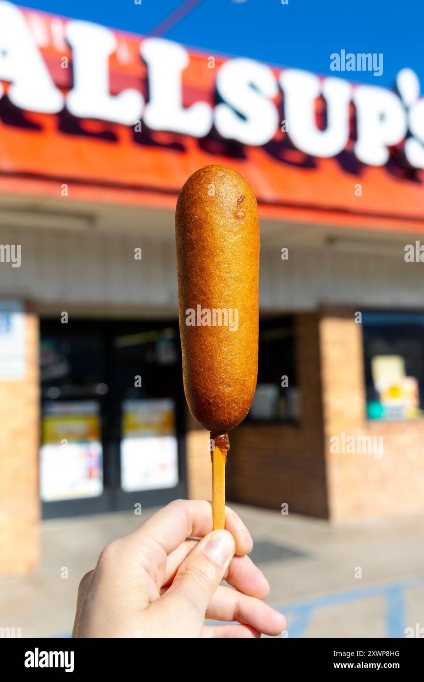 Main tenant un chien de maïs - une nourriture de rue américaine composée d'une saucisse seineuse frite dans la pâte de semoule de maïs Banque D'Images