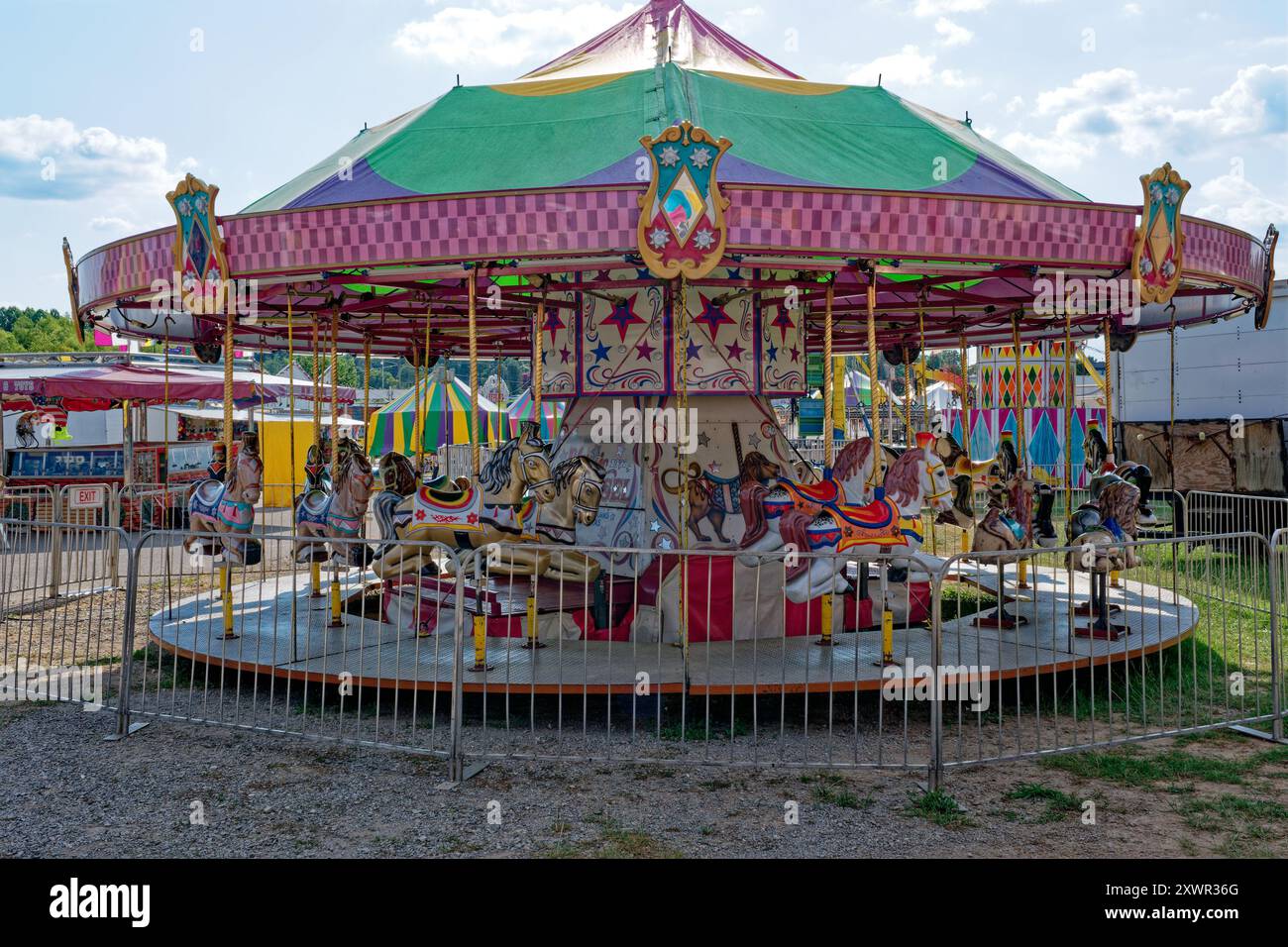 Joyeux vintage lumineux et coloré faire le tour du carnaval à la foire restaurée avec des chevaux en fibre de verre et des animaux avec tente en toile sur une journée ensoleillée dans s. Banque D'Images Joyeux vintage lumineux et coloré faire le tour du carnaval à la foire restaurée avec des chevaux en fibre de verre et des animaux avec tente en toile sur une journée ensoleillée dans s. Banque D'Images