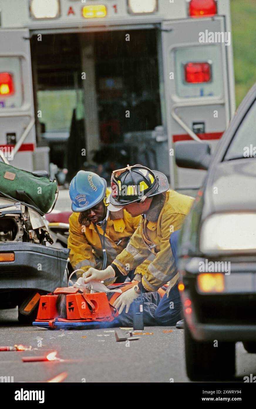 Premiers intervenants les EMT fournissent une aide médicale aux victimes d'un accident de la route alors que la circulation continue à circuler à proximité. Banque D'Images