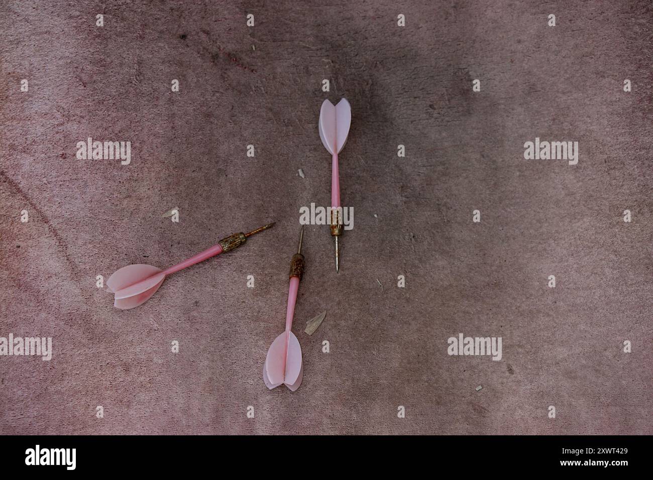 Vieilles fléchettes rouillées sales reposent sur un tissu rose, jouez Banque D'Images