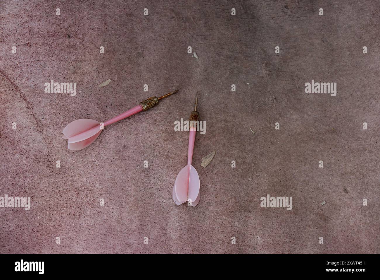 Vieilles fléchettes rouillées sales reposent sur un tissu rose, jouez Banque D'Images