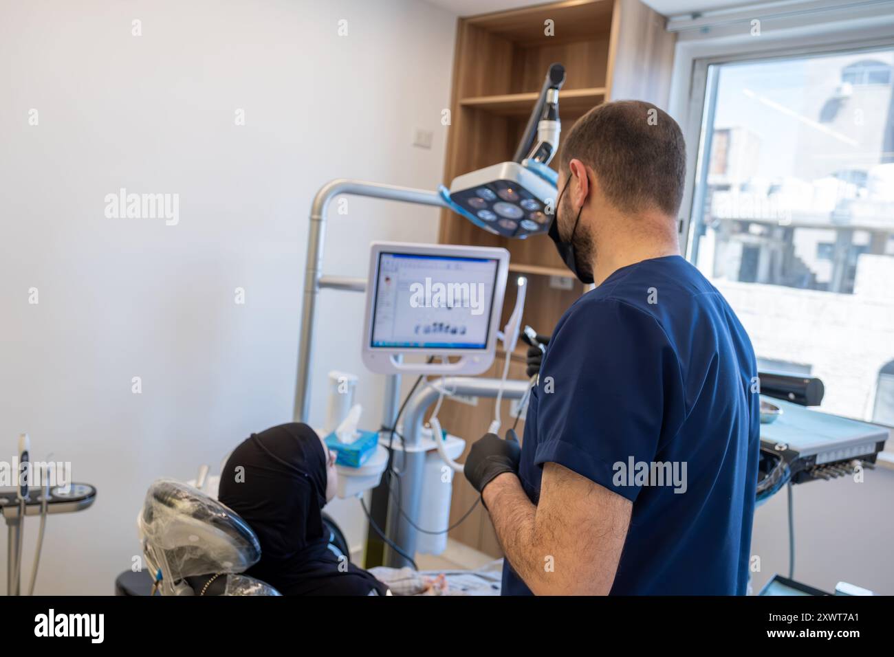 dentiste montrant des scans dentaires pour la patiente musulmane et parlant de sa situation pour le traitement plus tard Banque D'Images