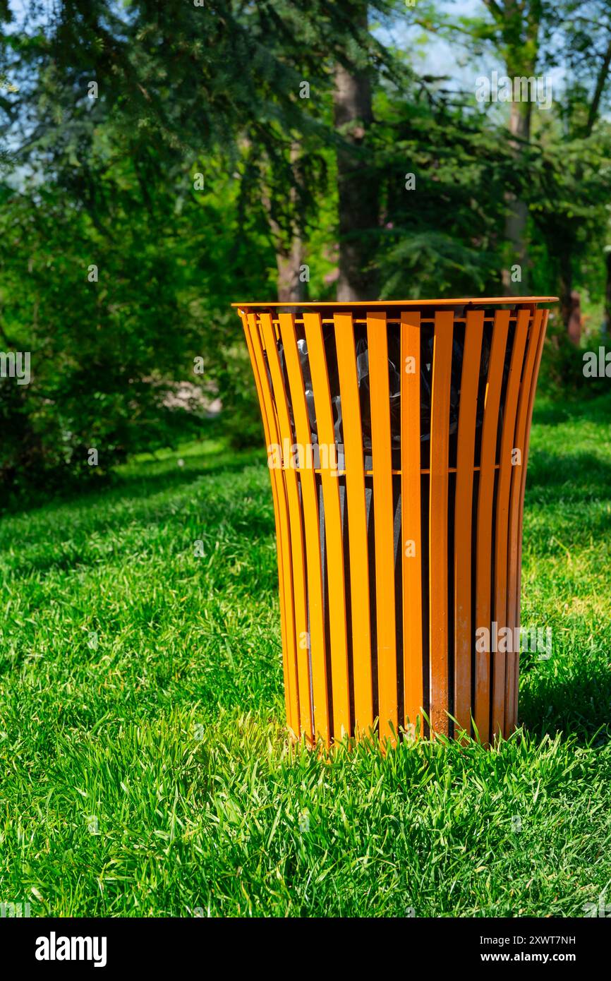 Poubelle dans un parc verdoyant. Une poubelle colorée dans l'herbe. Concept de propreté dans la ville, un geste de civisme et de respect Banque D'Images