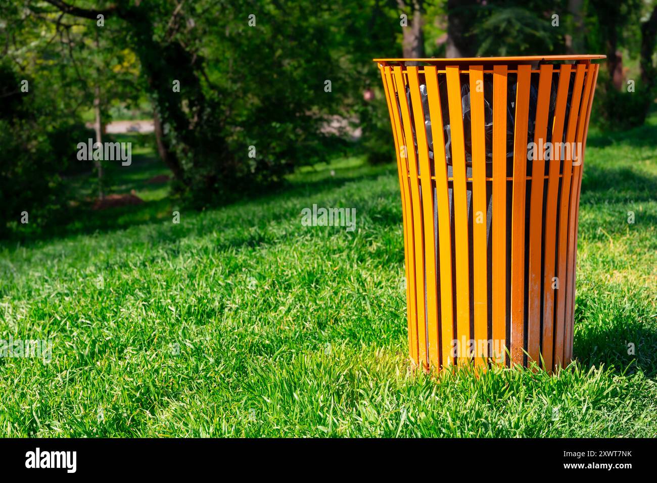 Poubelle dans un parc verdoyant. Une poubelle colorée dans l'herbe. Concept de propreté dans la ville, un geste de civisme et de respect Banque D'Images