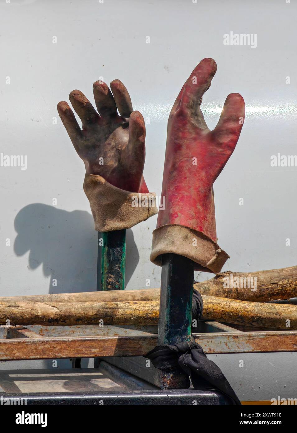 Paire de gants rouges de travailleur en caoutchouc sale : environnement de service public isolé sur fond blanc - lumière et ombre. Banque D'Images