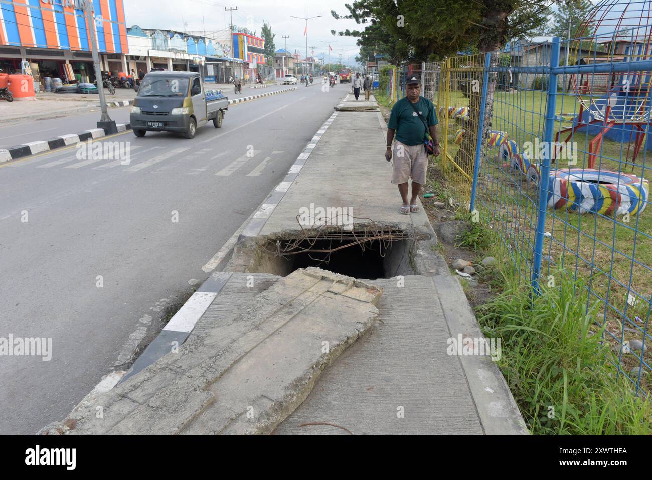 Wer in Wamena auf dem Bürgersteig der Hauptstraße läuft, muss aufpassen, nicht abzustürzen. Unter dem Gehweg verläuft ein Abwasserkanal und einzelne Betonplatten des Gehwegs sind beiseite geschoben. *** Toute personne marchant sur le trottoir de la rue principale de Wamena doit faire attention à ne pas tomber sous le trottoir, où un égout coule en dessous et où certaines dalles de béton du trottoir ont été écartées Banque D'Images