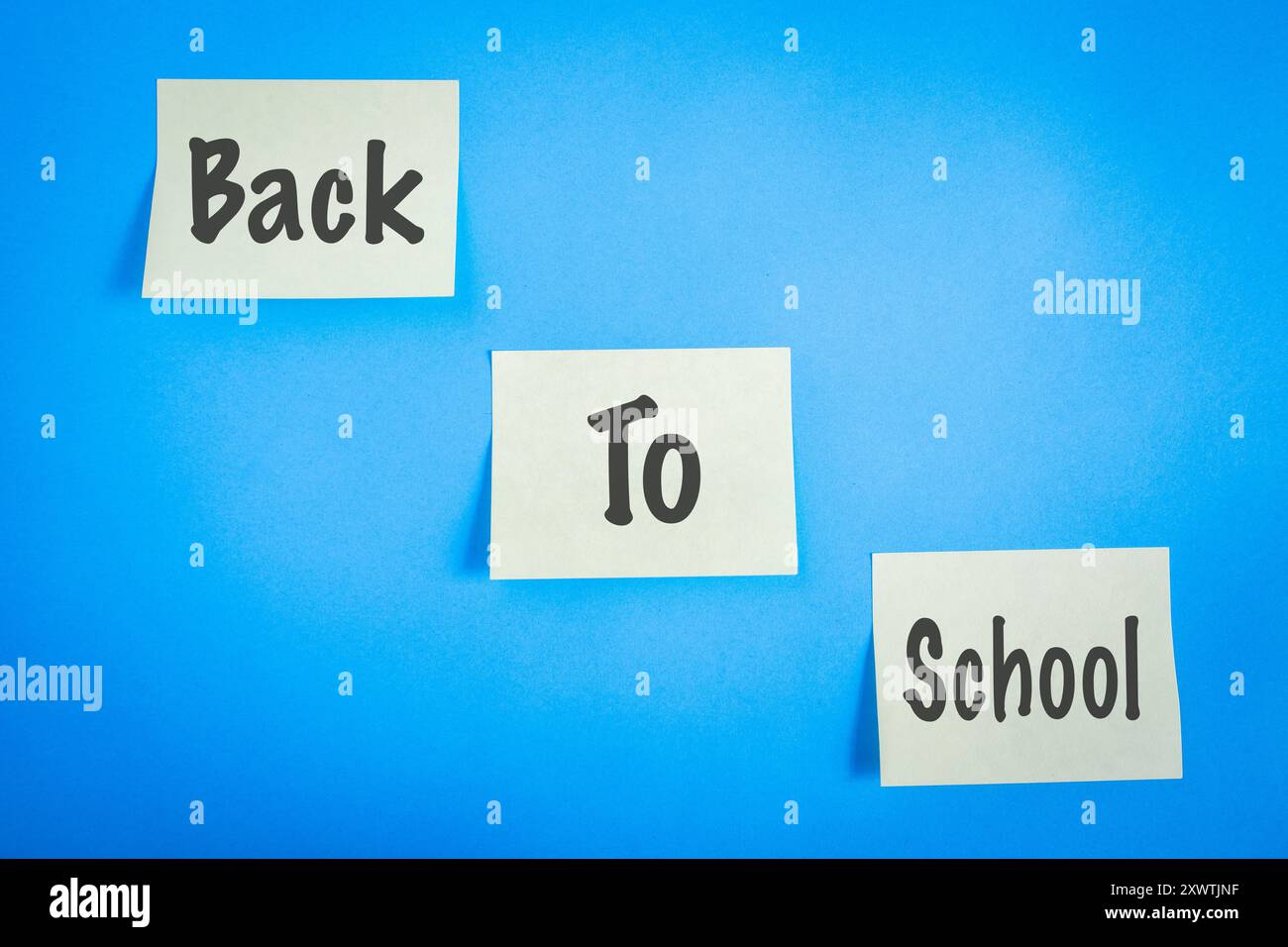 Trois notes adhésives, avec les mots retour à l'école dessus. Sur fond bleu. Banque D'Images