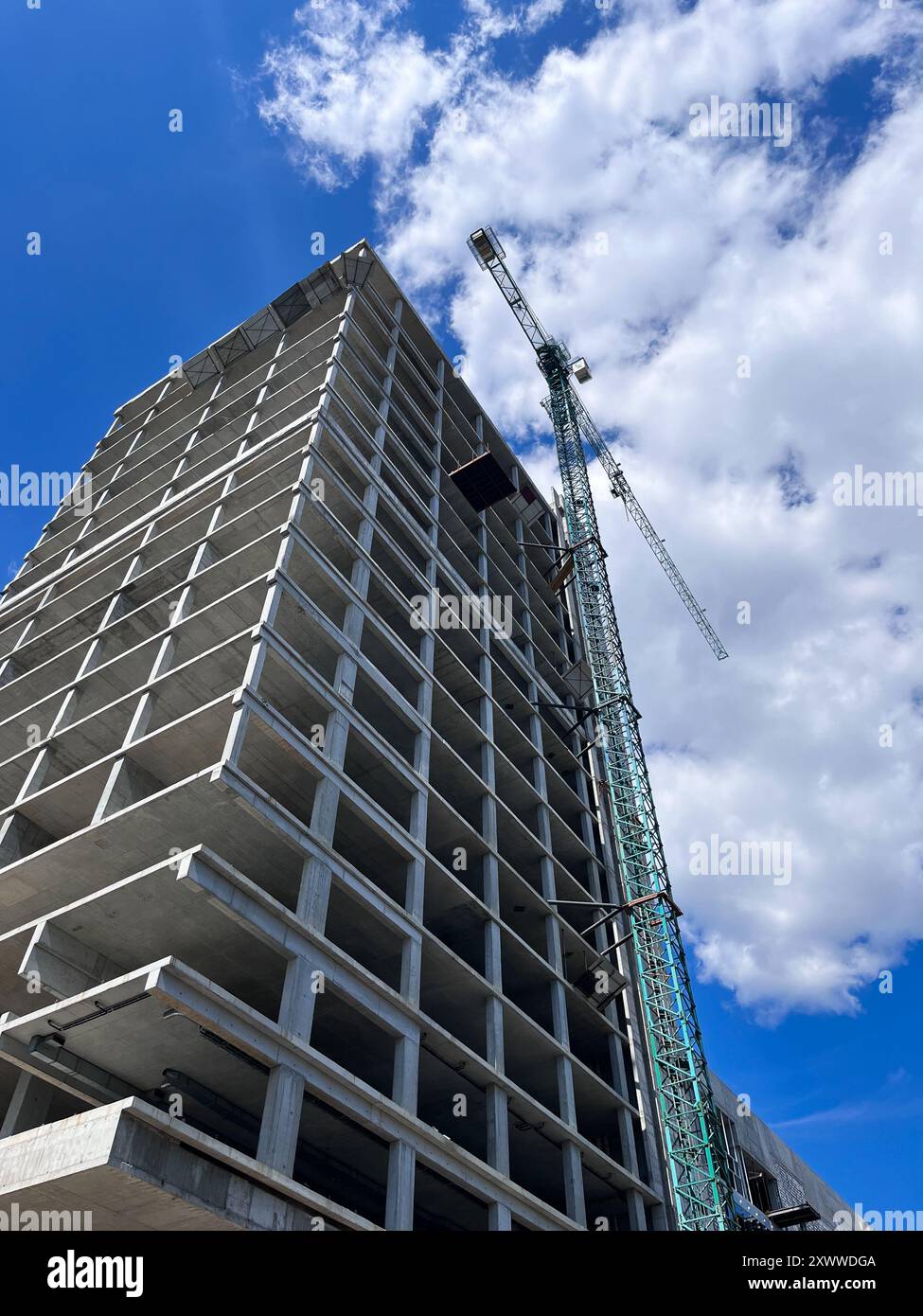 une grue de construction sur le fond d'un ciel bleu avec des nuages. chantier de construction. verticalement Banque D'Images