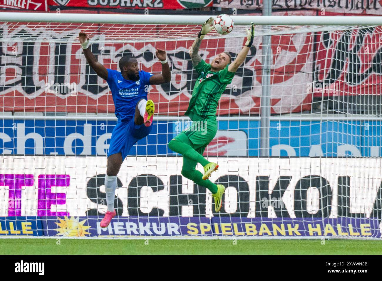 Halle, Deutschland 20. Août 2024 : Regionalliga Nord/Ost - 2024/2025 - Hallescher FC vs VSG Altglienicke Im Bild : v. Li. im Zweikampf Manasse Eshele (Altglienicke) und Torhüter Sven Müller/Mueller (Halle) Banque D'Images