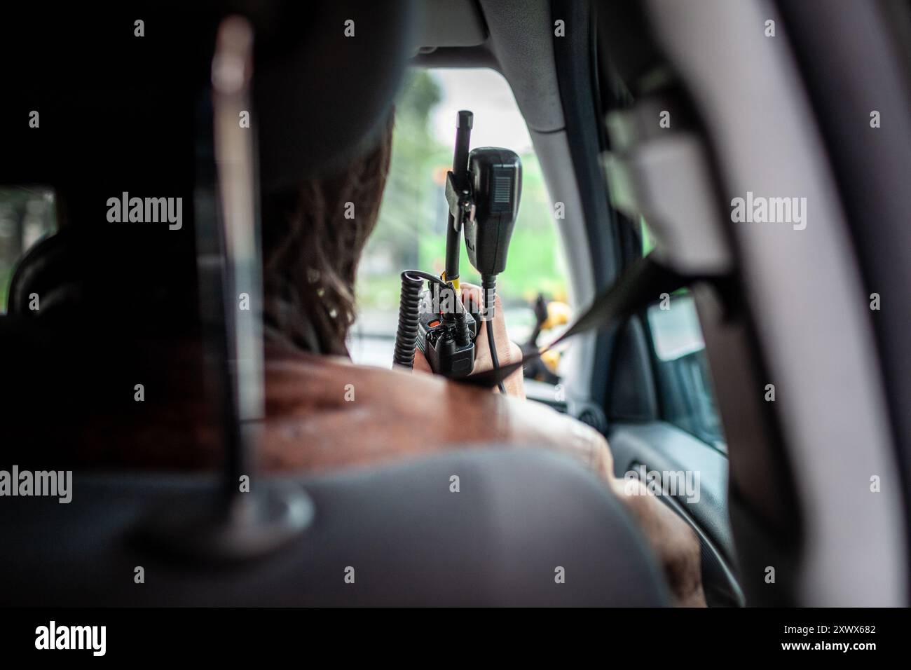 Un policier secret en service, observant attentivement les environs depuis le siège arrière d'une voiture à Hanovre, 2011. L'officier tient une radio, symbolisant la communication et les mesures d'application de la loi pendant les patrouilles de routine. Banque D'Images