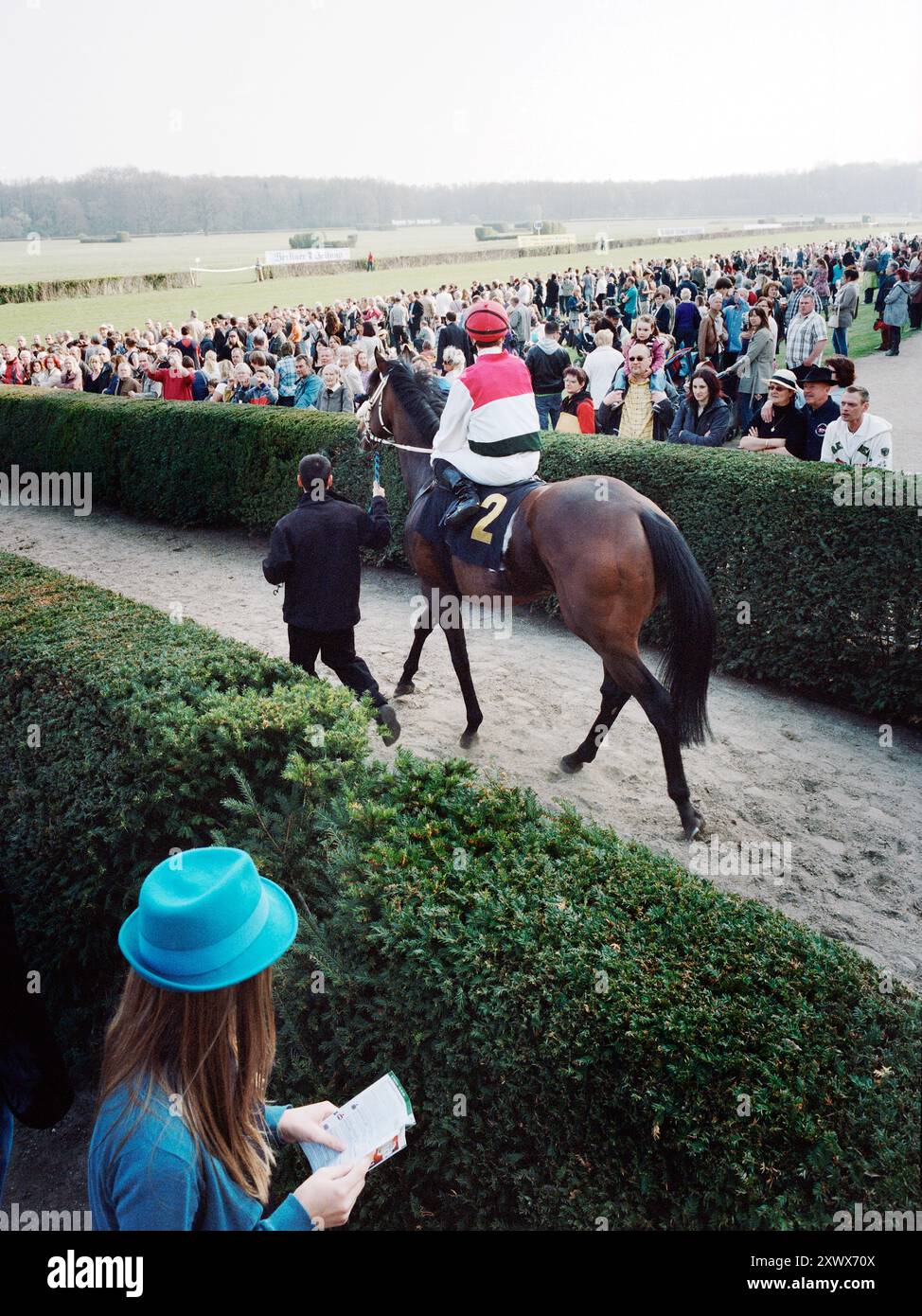 Le jockey Andreas Suborics à cheval d'OVERDOSE se prépare pour une course palpitante lors de l'ouverture de la saison 2011 sur la piste de Hoppegarten à Berlin. La foule regarde avec impatience l'excitation grandissante pour la course à venir. Banque D'Images